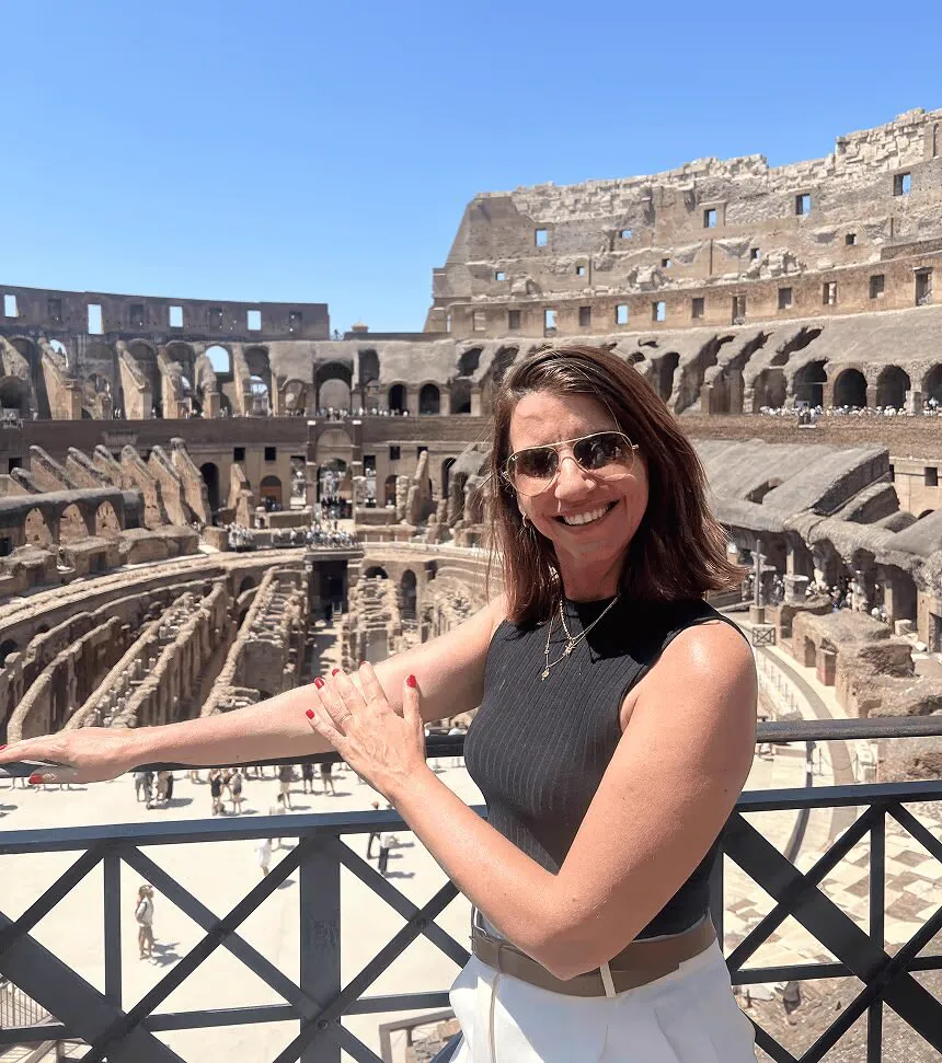 Sandra sorrindo, de óculos escuros, no alto do Coliseu em Roma